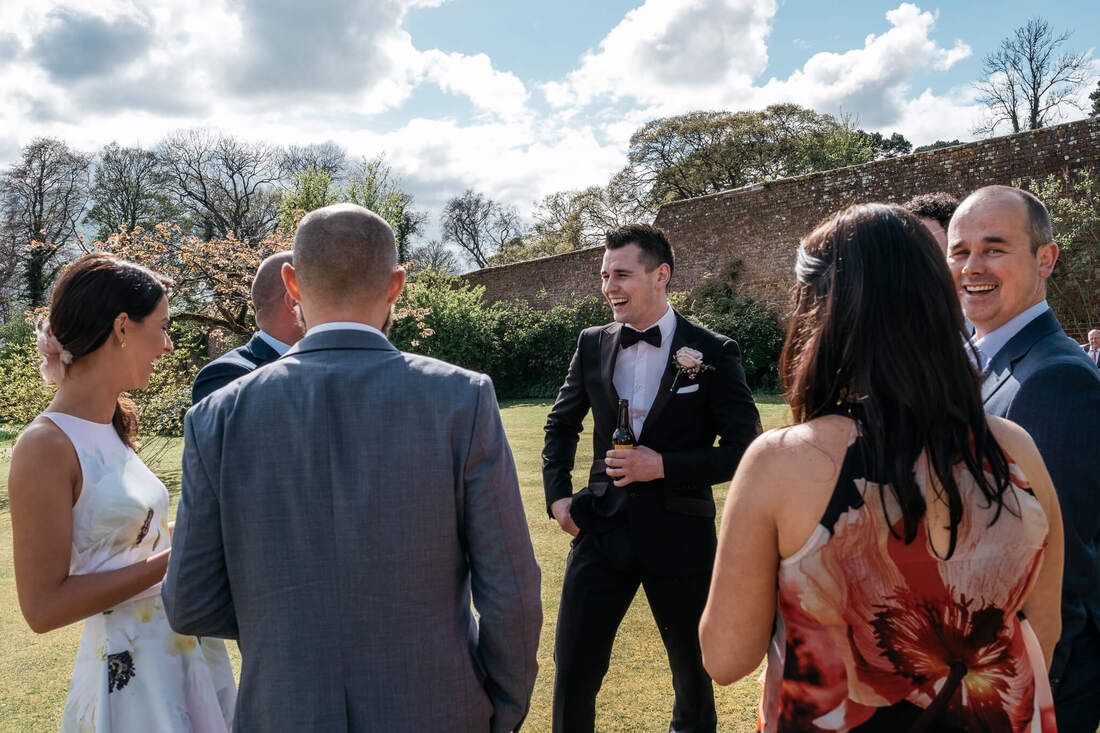 Guests & the bridal party chat at a sunny spring wedding in Ballyscullion Park