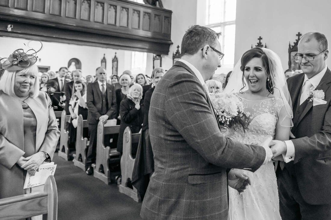 A bride can't contain her smile as she meets her groom at the altar