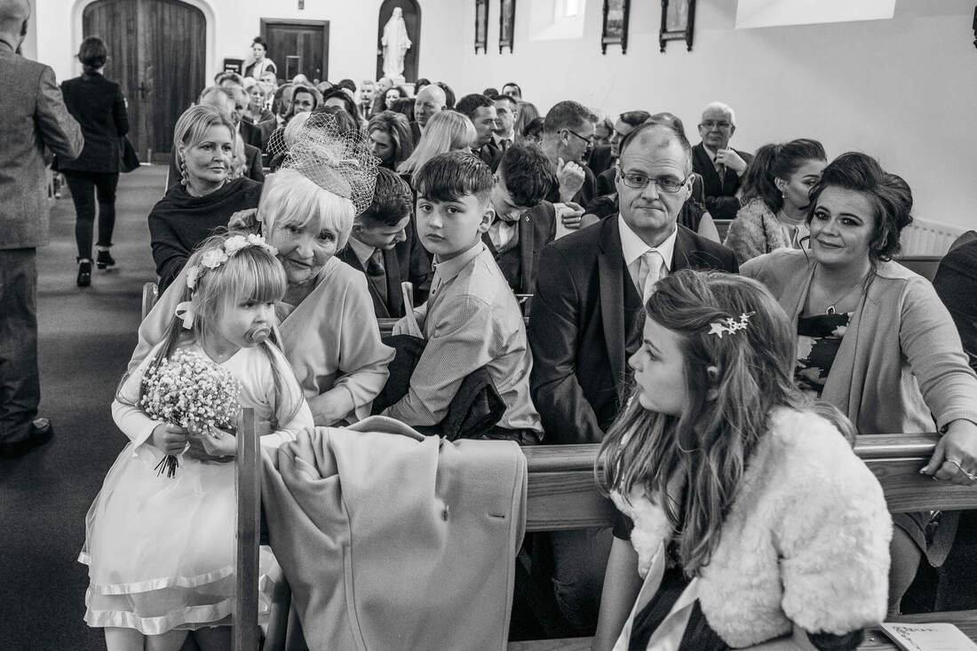 Family sitting in the front two pews after the wedding while the bride & groom are signing the register