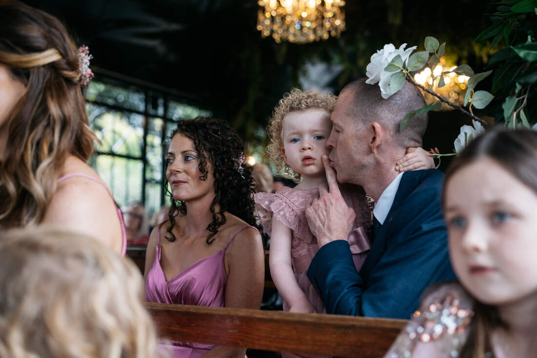 A young flower-girl is shushed by her dad during the wedding ceremony