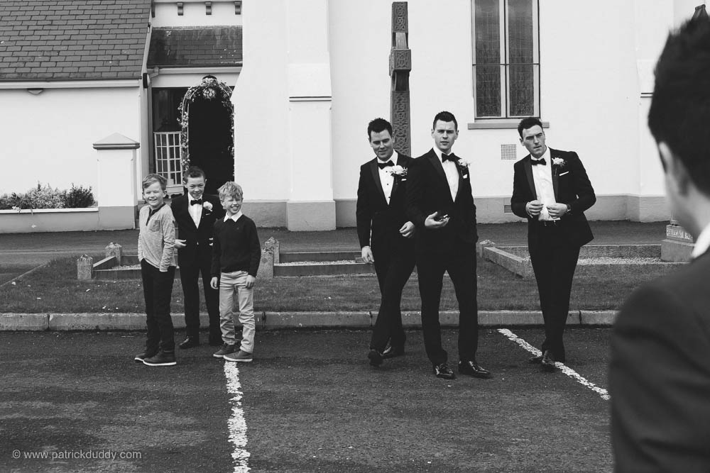 Black and white wedding photography of Groom & Groomsmen preparing outside chapel, prior to wedding at Ballyscullion Park Wedding Venue by Patrick Duddy Documentary Candid Wedding Photography