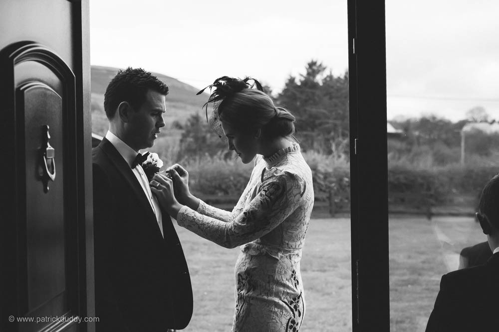 Groomsman has pinhole flower attached before wedding in black and white candid wedding photography by patrick duddy wedding photographer
