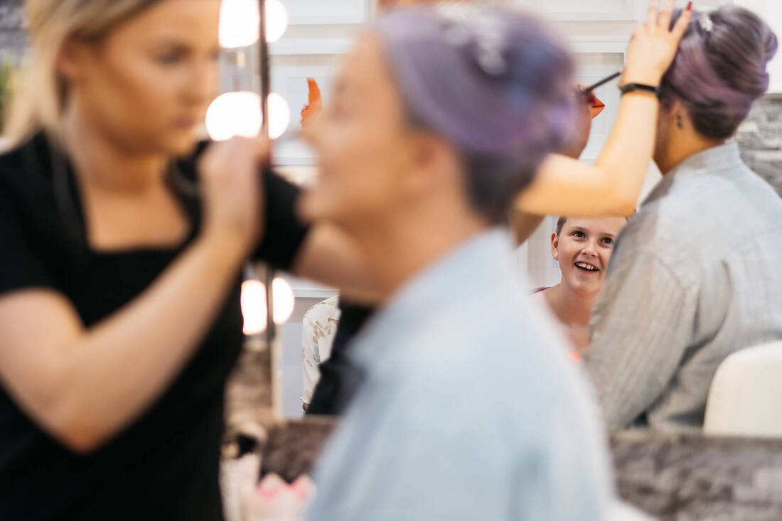 A photograph of a flower girl laughing as the bride gets her make up applied on the morning of her wedding in Derry