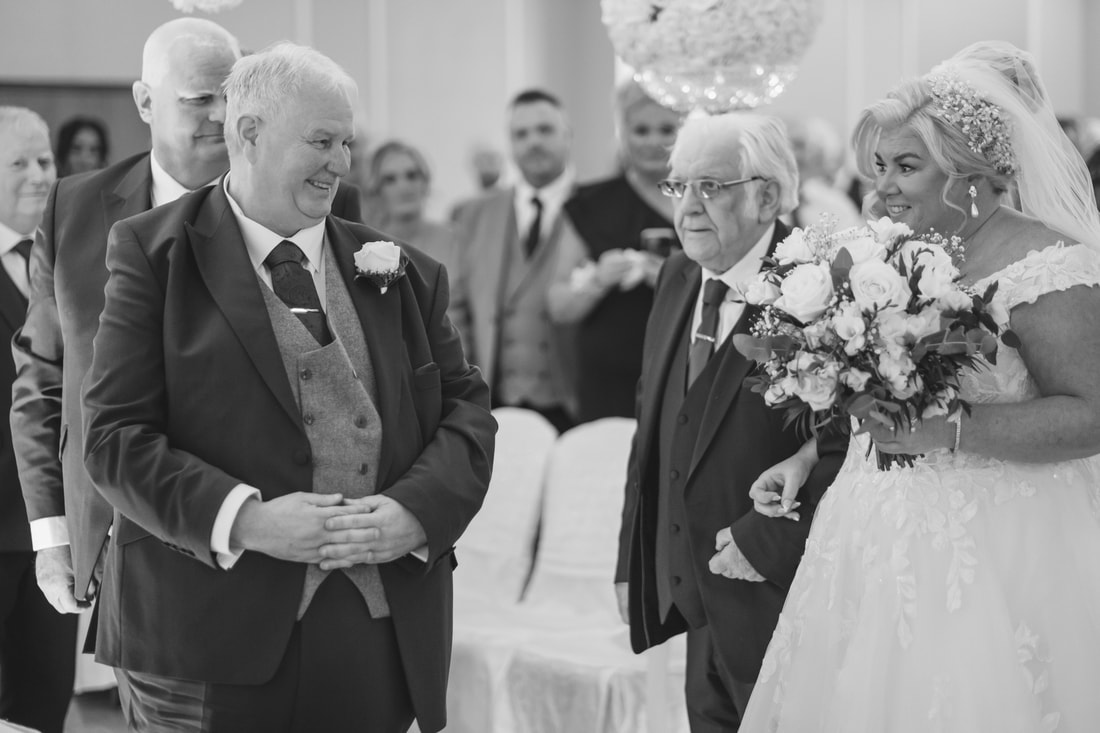 A black and white photograph of the bride and groom exchanging glances at the top of the aisle before their Derry Civil Ceremony Wedding 