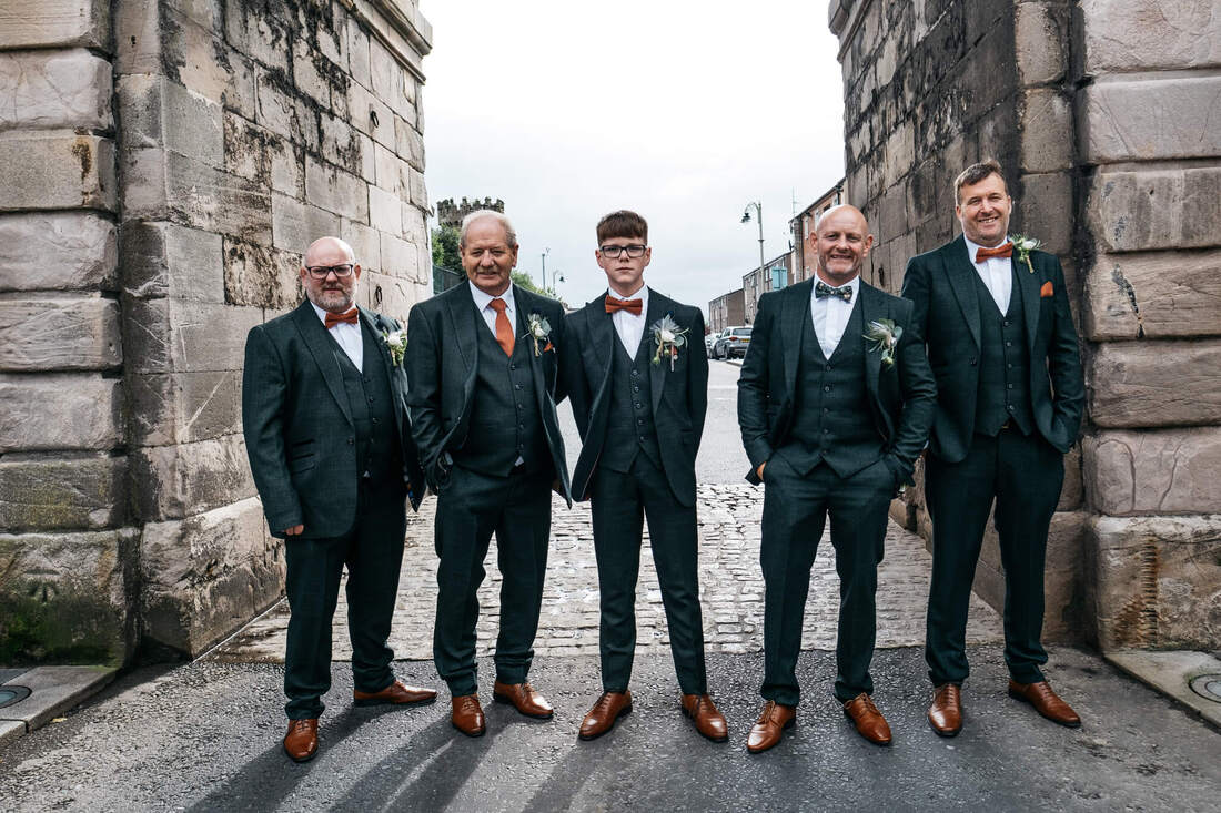 A grooms and groomsmen stand at Bishops Gate Derry