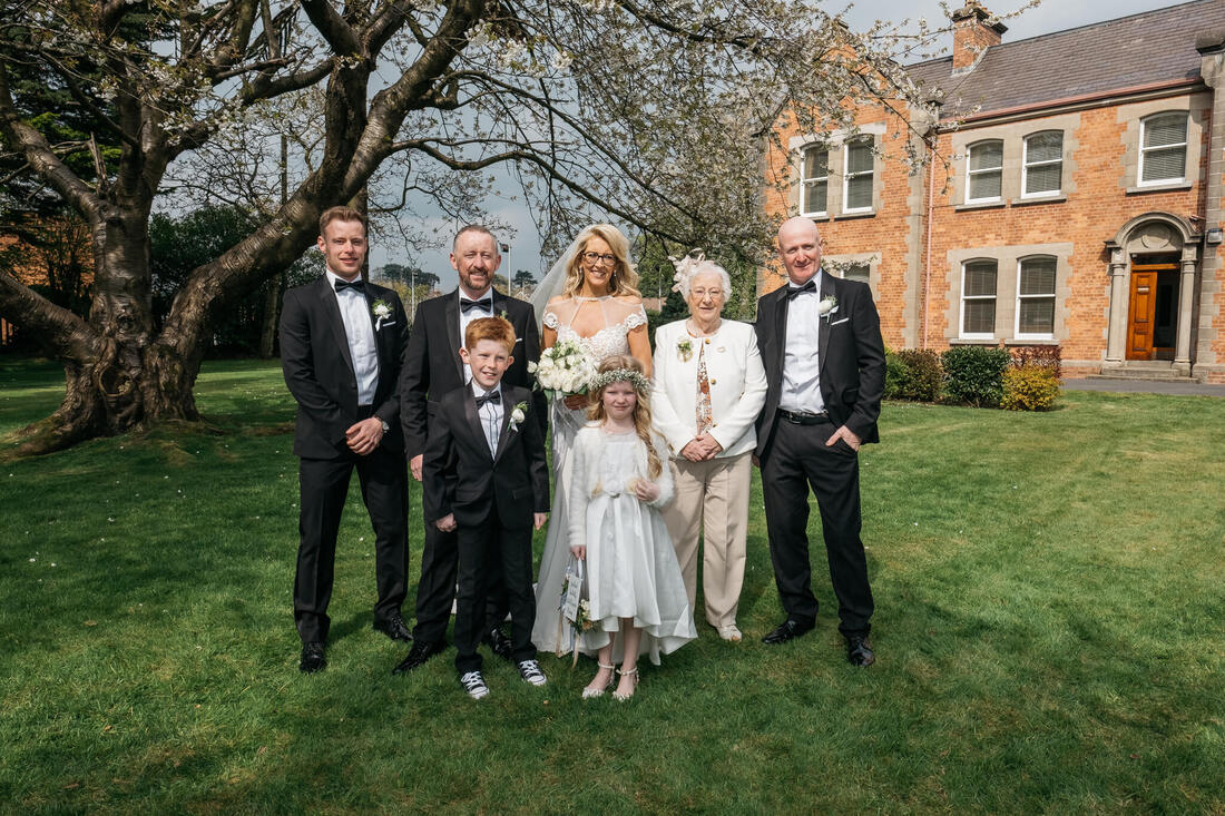 The Bride and Groom with their family in the grounds of St Patricks Church Pennyburn Derry on their wedding day