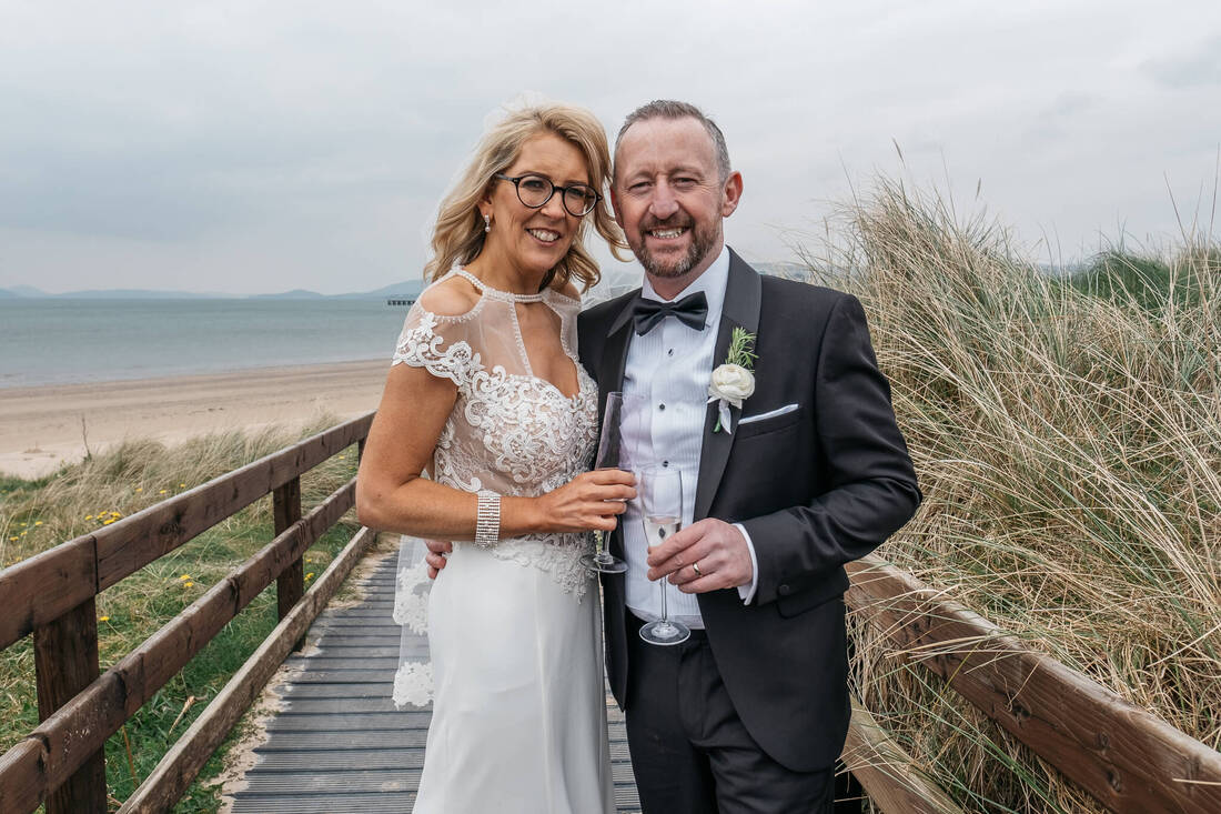 A close up photography of a bride and groom on the wooden walkway to Buncrana Beach on the way to their Inishowen Gateway Hotel Wedding