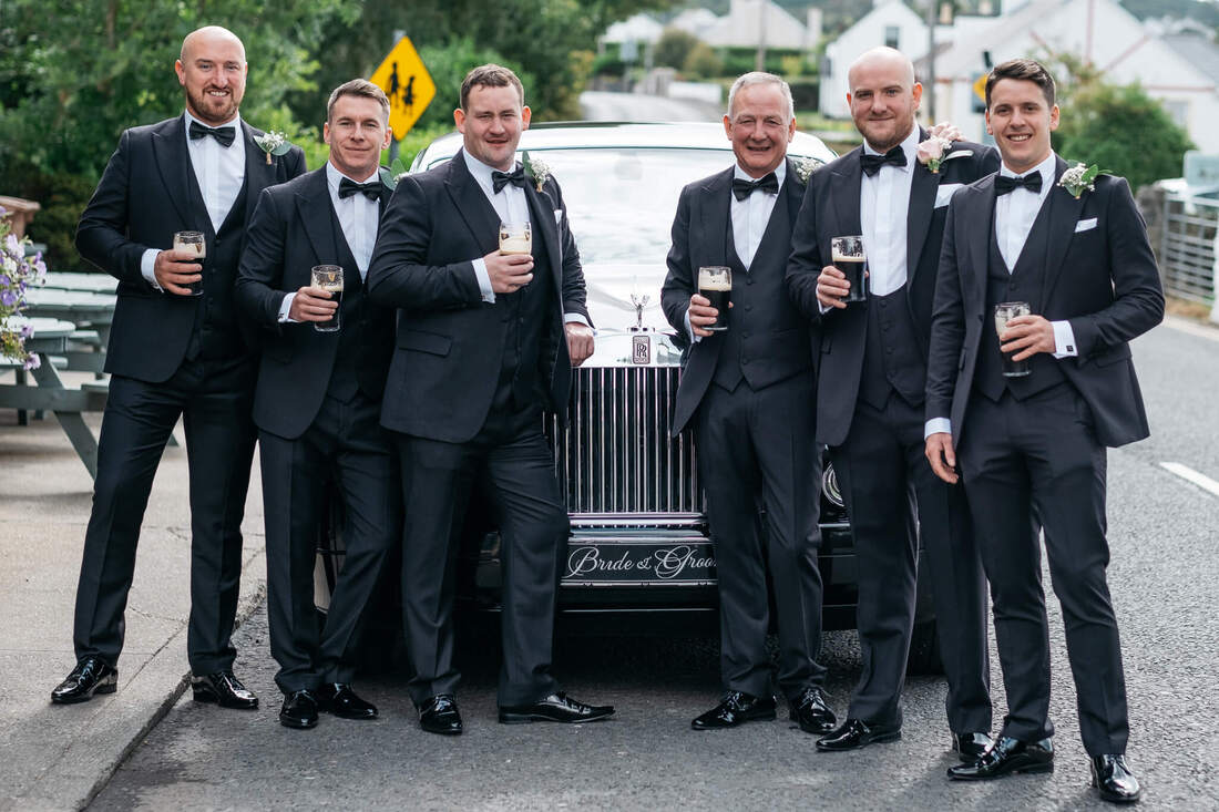 A grooms and groomsman holding pints of Guinness outside McGrorys Hotel Donegal