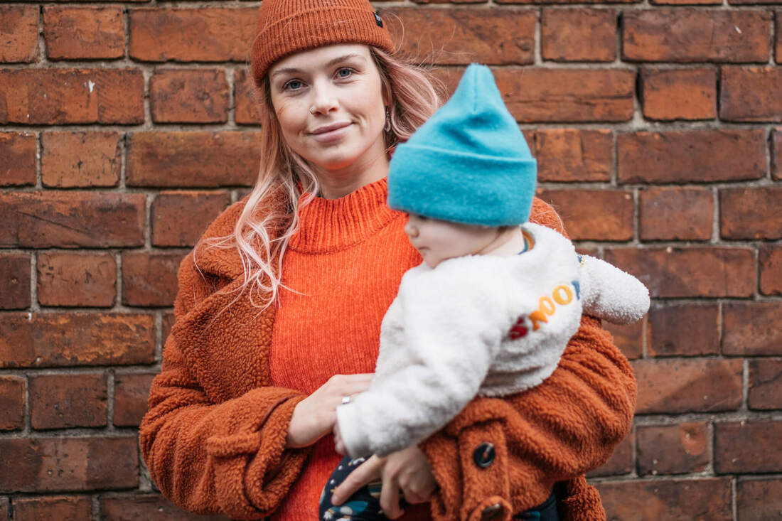 A mum holding her young son in her arms in front of a traditional red brick wall