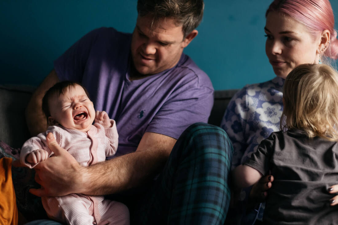 Mum, Dad, Son & Daughter - with dad looking worried while holding his crying baby girl
