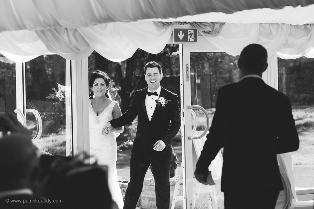 The bride and groom smile as they are about to enter their wedding reception in Ballyscullion Wedding Venue