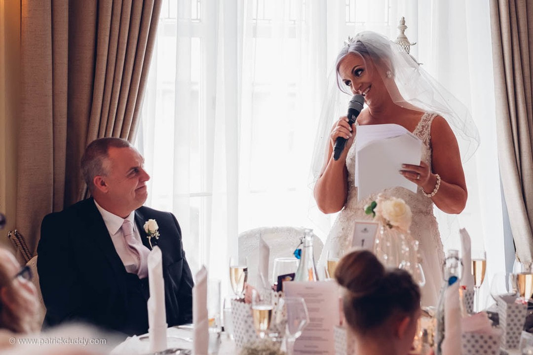 the groom looks on as his bride toasts him during her wedding speech in Bishops Gate Hotel Derry