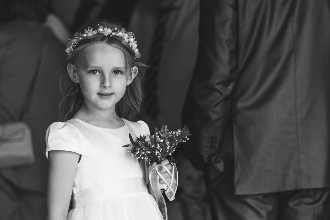 A young wedding guest holding a bouquet as guest arrive at the wedding ceremony