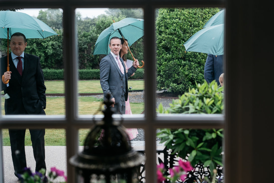 Documentary wedding photography from The Old Rectory, Killyman by Patrick Duddy Photography - guests with brollys arrive