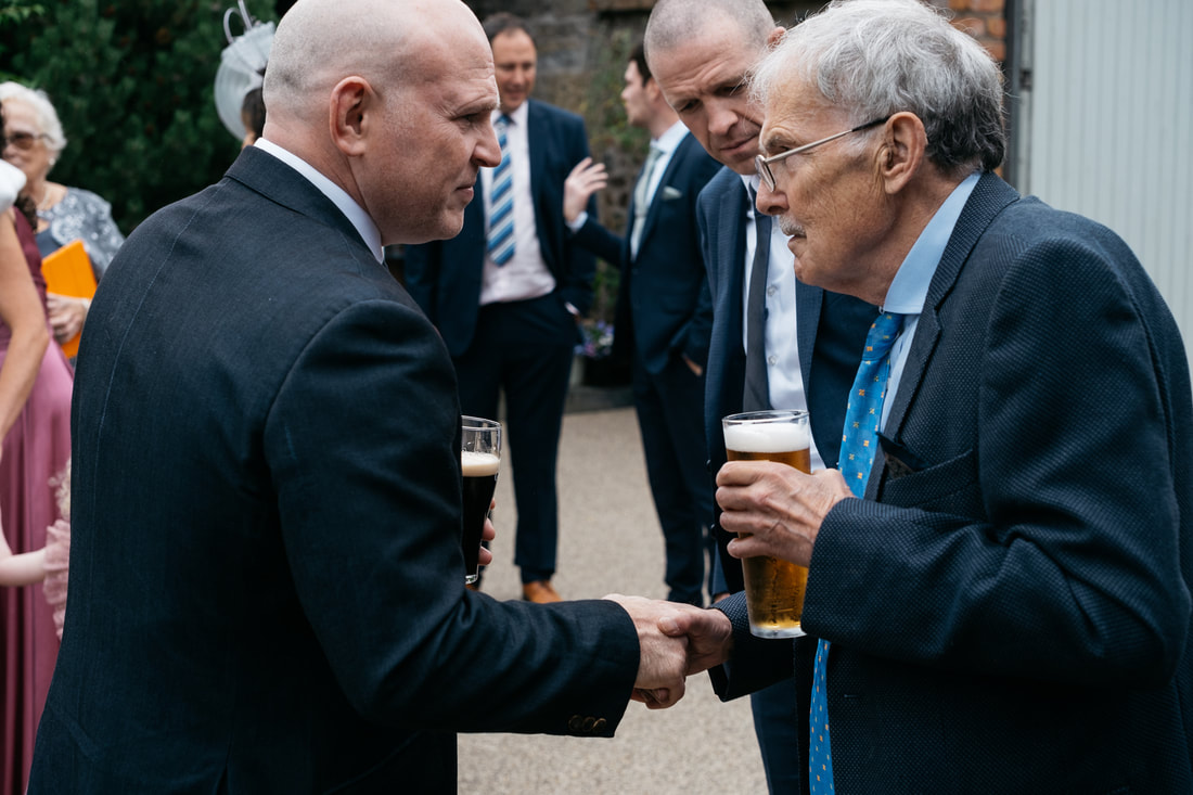 Documentary wedding photography from The Old Rectory, Killyman by Patrick Duddy Photography - a hand shake and a pint