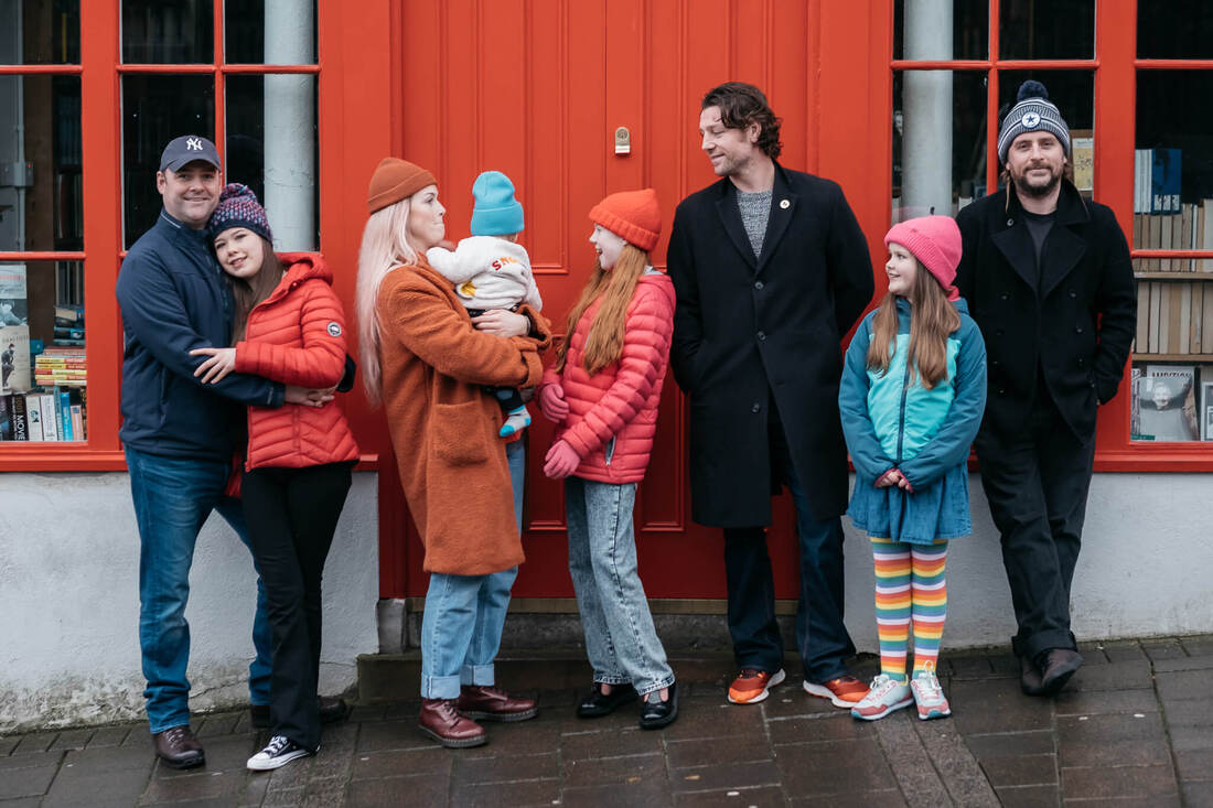 Three brothers & a sister, together with their children outside a book store in Derry
